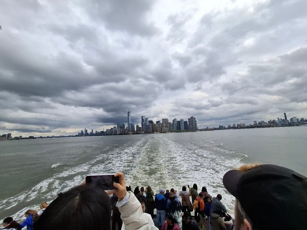 "Visitors aboard a Statue of Liberty ferry enjoy dramatic views of the Manhattan skyline, illustrating the best time to visit the Statue of Liberty in the morning versus sunset."