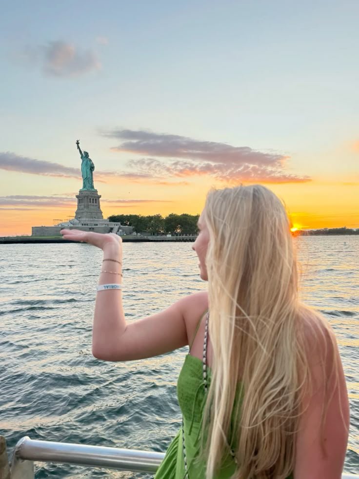Visitor enjoying a free close-up view of the Statue of Liberty from the waterfront at sunset, demonstrating that you can admire the iconic landmark without purchasing a ferry ticket.