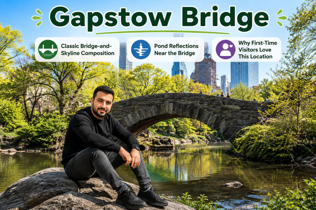 Iraqi traveler smiling while sitting on a large rock beside Gapstow Bridge in Central Park, with peaceful pond reflections, iconic stone bridge, and Manhattan skyline creating a scenic photography location.